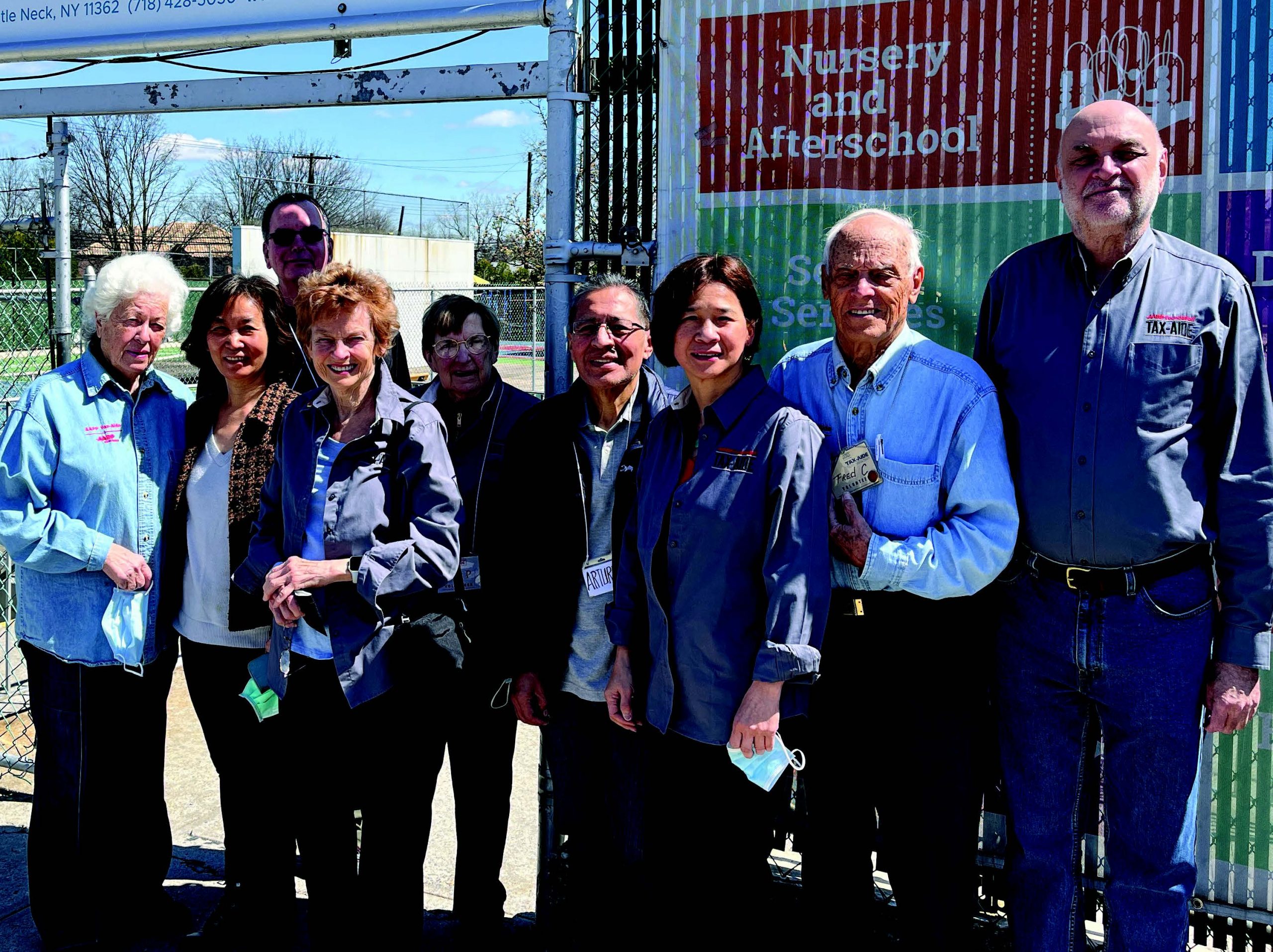A group of AARP members standing in front of a fence.