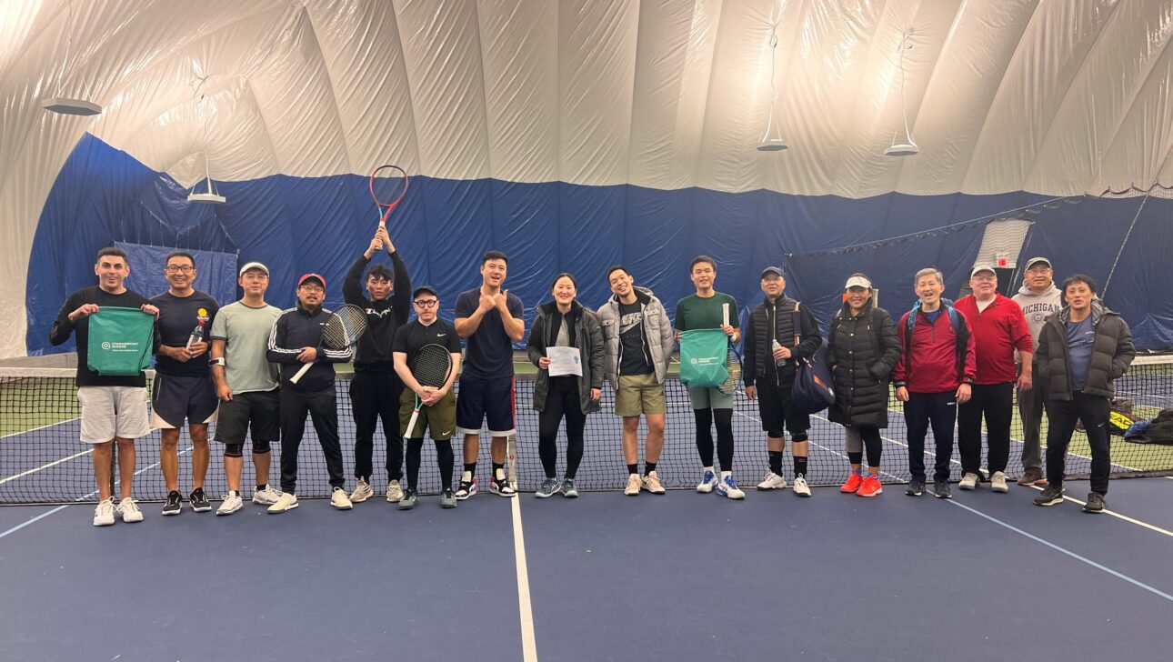 A group of people standing on a tennis court.
