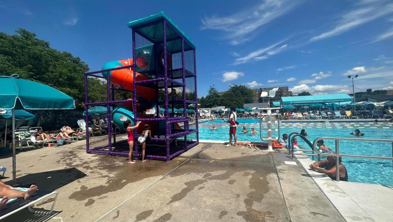 A group of people at a swimming pool with a slide.