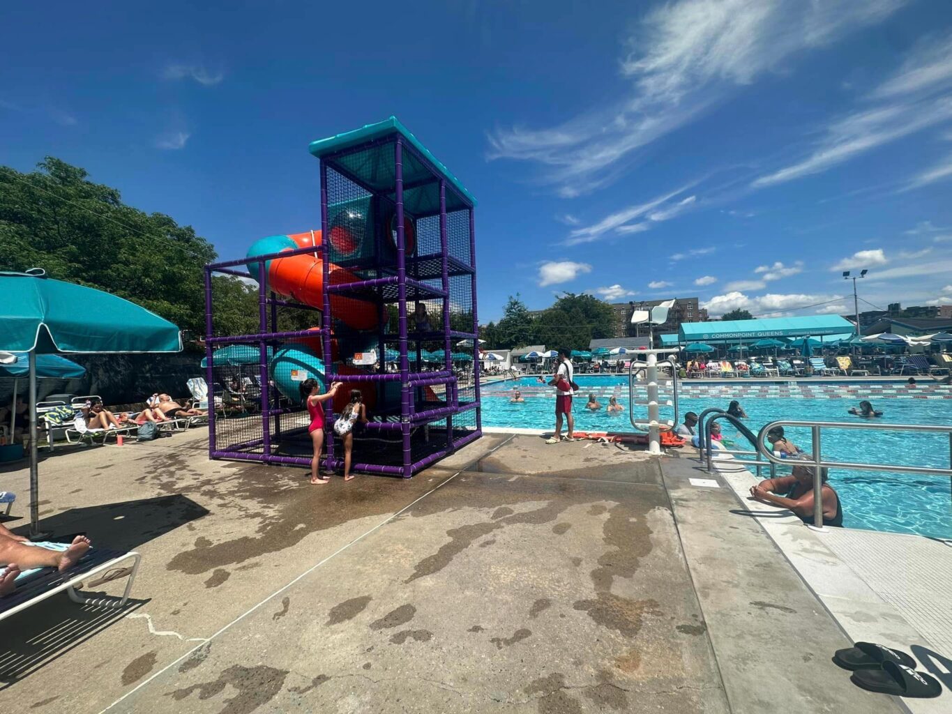 A group of people at a swimming pool with a slide.