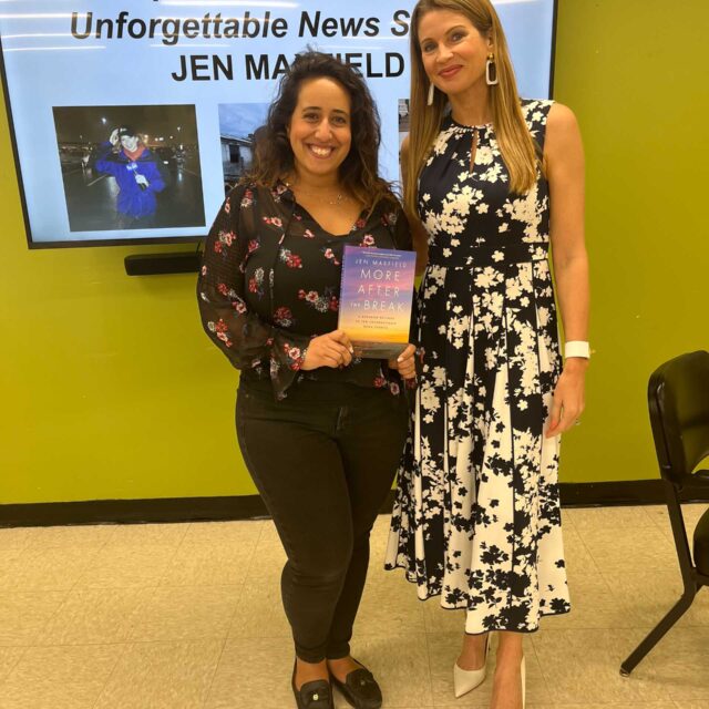 Two women standing in front of a screen with a book.