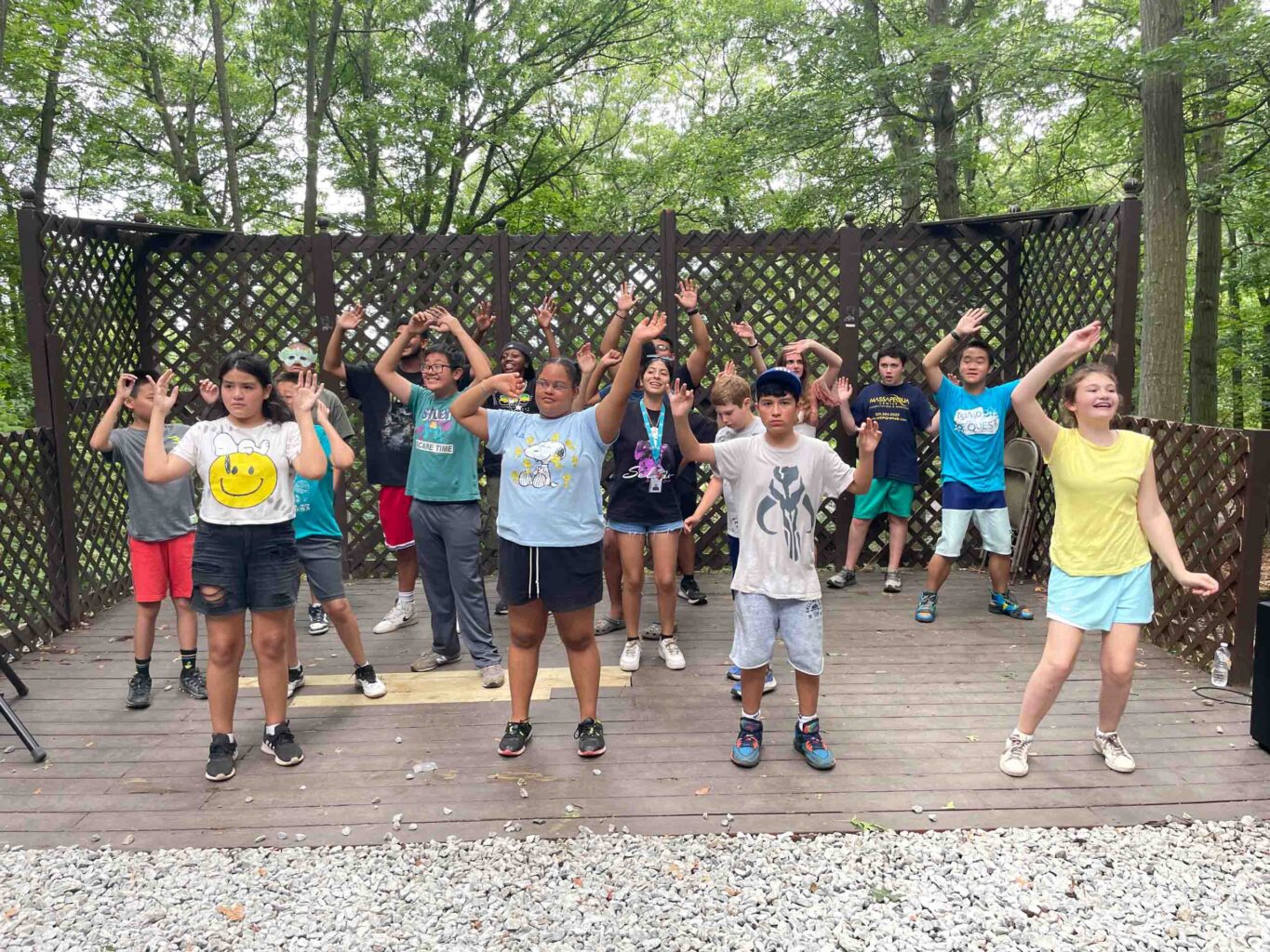 A group of people standing on a deck with their hands up.