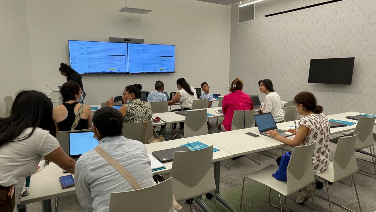 A group of people sitting in a room with laptops.