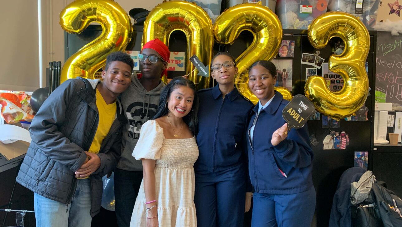 A group of people posing in front of balloons with the number 2023.