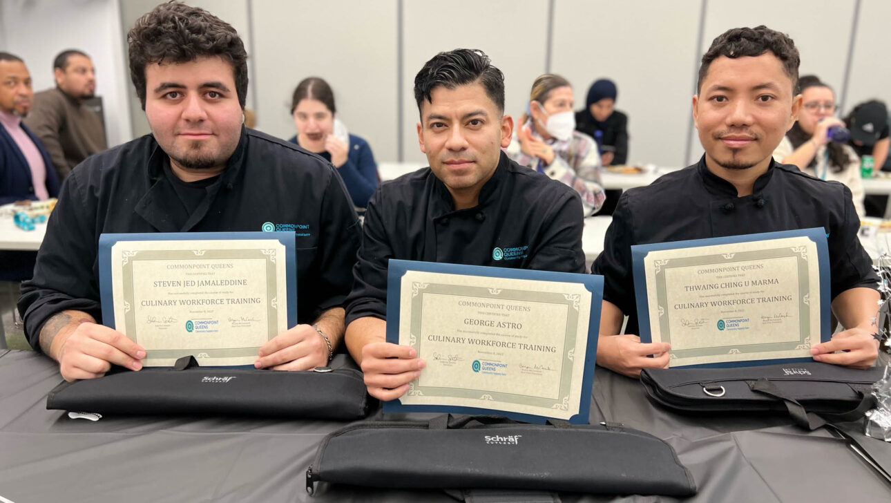 Three chefs holding certificates in front of a table.