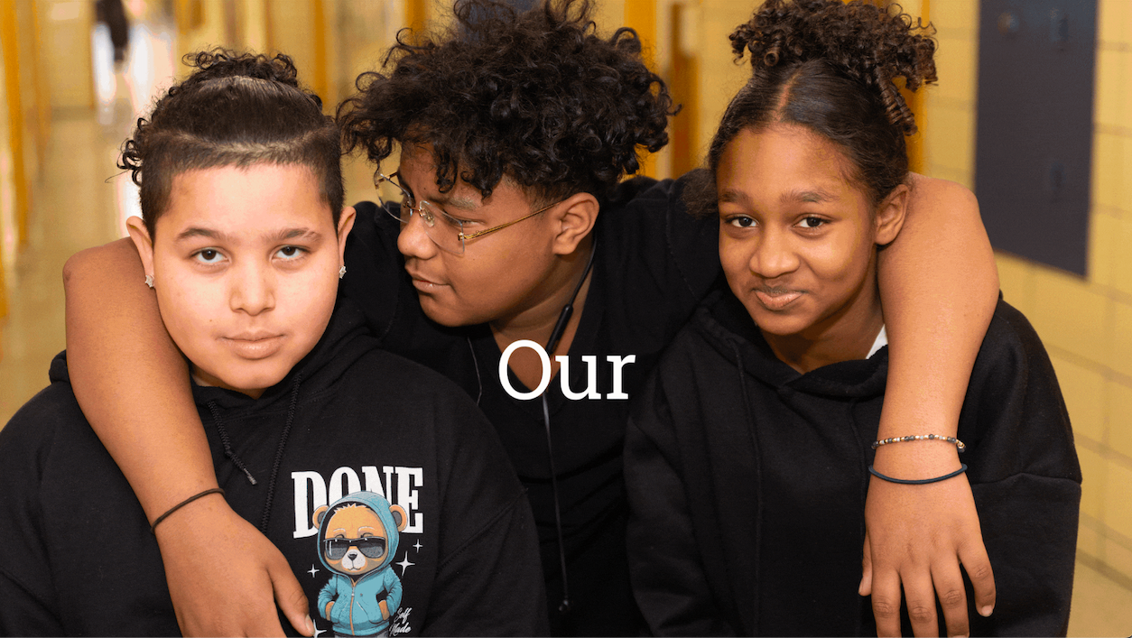 Three children stand in a hallway, two with dark curly hair and one with a short haircut. The central child places an arm around the other two. Text overlay reads "Our Commonpoint After School Moments.