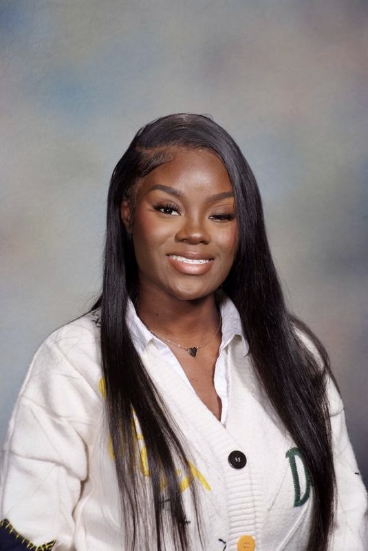 Roberta Gordon, a woman with long straight hair and a white sweater, smiles in front of a soft, gradient background.