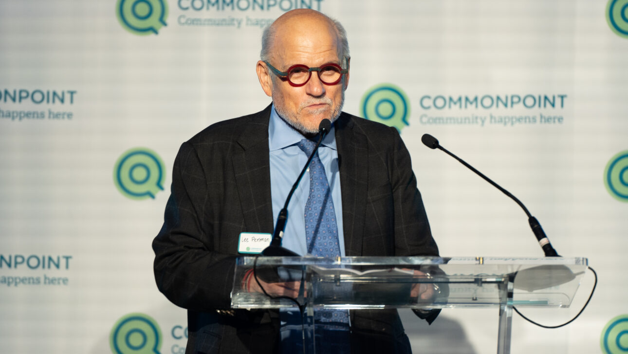 An older man in a suit and glasses speaks at a clear podium with microphones during the Commonpoint Gala. The backdrop displays the Commonpoint logo and the text "Community happens here.
