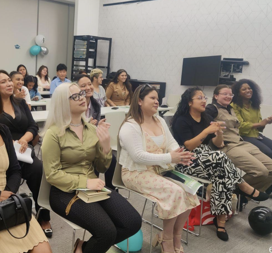 People sit in rows in a modern classroom, listening attentively to an engaging session about the digital court reporting field. Decorations include balloons and a small banner featuring Commonpoint. Most attendees are women, dressed in business casual attire, eager to learn more about the court reporting program.