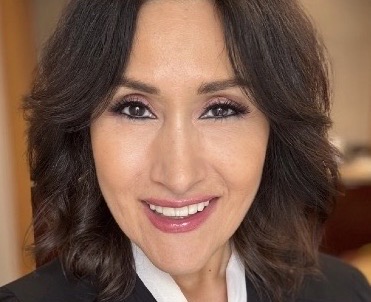 A smiling woman with shoulder-length brown hair looking toward the camera.